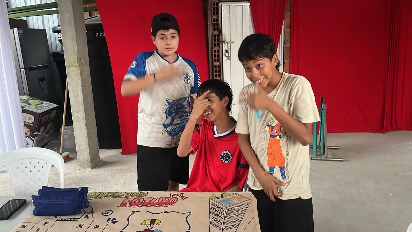 Tres estudiantes hacen muecas detrás de su mural «Nuestro futuro»