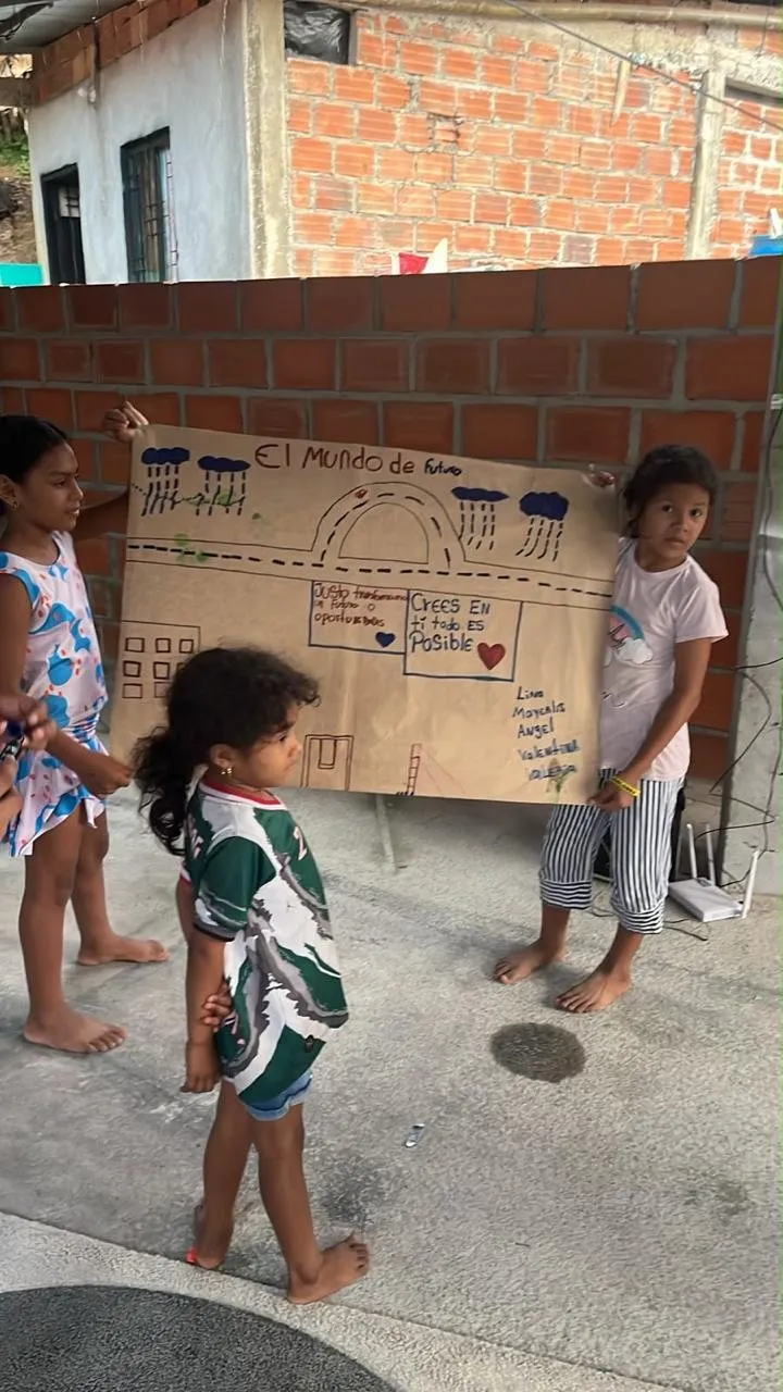 Las niñas sostienen su mural «El mundo del futuro» contra el muro de ladrillo