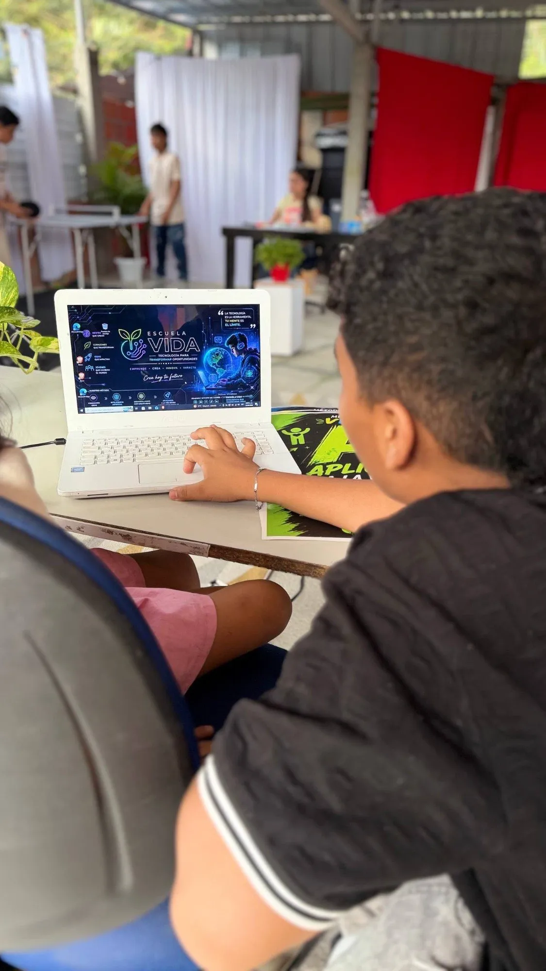 Un estudiante trabaja en un portátil con el fondo de Escuela VIDA