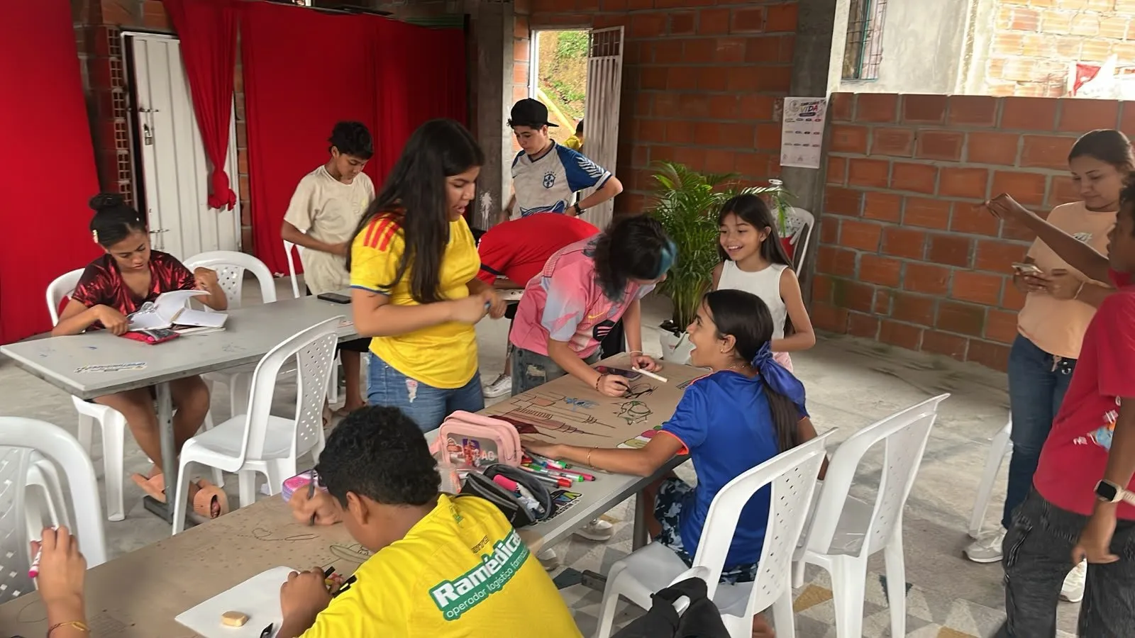 El salón completo trabajando en los murales, con el telón rojo al fondo